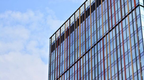 La fachada acristalada de un edificio de oficinas con cielo reflejado. Edificios de arquitectura moderna exterior  - Foto, imagen