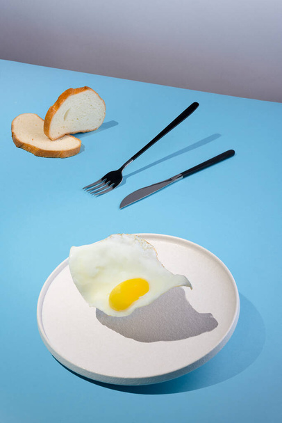 flying fried eggs plate on the modern blue background, vertical orientation - Photo, Image