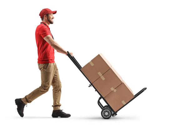 Delivery man pushing a hand truck with cardboard boxes isolated on white background - Fotó, kép