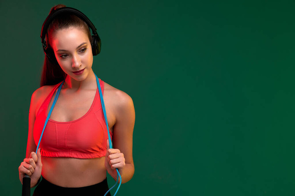 Attractive sport woman with skipping rope and strong woman listen music in headphones indoors - Fotografie, Obrázek