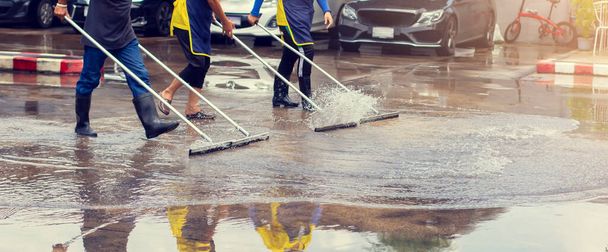 Selective focus to worker using wiper or squeegee to clean floor surface. Staff cleaning floor with wiper. The concept of cleaning service. - Photo, Image