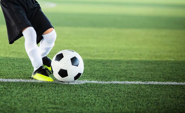 子供のサッカー選手の動きのぼやけたサッカーに選択的な焦点は、人工芝でそれを撮影します。サッカー試合のためのサッカー選手のトレーニング. - 写真・画像