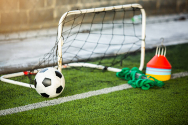 Θολή μπάλα ποδοσφαίρου με μίνι γκολ και εξοπλισμό προπόνηση ποδοσφαίρου σε πράσινο τεχνητό χλοοτάπητα. Αθλητισμός. - Φωτογραφία, εικόνα