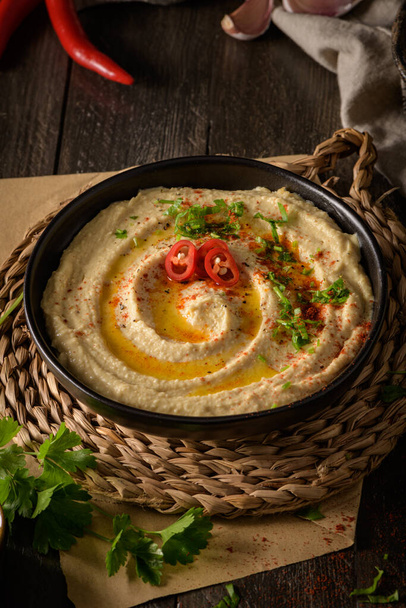 Delicious hummus in ceramic bowl. Colorful snack composition on a black wooden background. - Foto, immagini