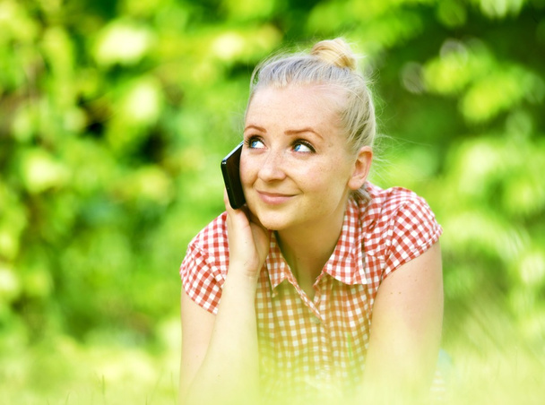 Young attractive woman lying on lawn with phone. - Φωτογραφία, εικόνα
