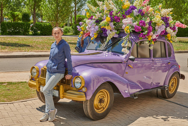 een meisje staat bij de lila auto - Foto, afbeelding