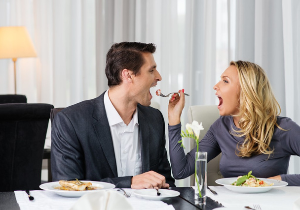 Χαρούμενο ζευγάρι σε ένα εστιατόριο με ποτήρια κόκκινο κρασί - Φωτογραφία, εικόνα