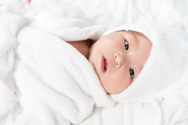 close up baby in soft bathrobe on a bed - Fotó, kép