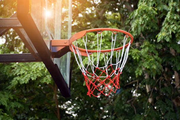 Баскетбольний кільце на відкритому тлі стрільби, розмитий і сонячне світло відредагований фон. М'який та вибірковий фокус на баскетбольному кільці
. - Фото, зображення