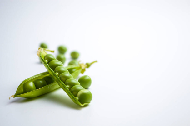Frische grüne Erbsenschoten und grüne Erbsen mit Sprossen auf weißem Holzgrund. Konzept der gesunden Ernährung, frisches Gemüse. - Foto, Bild
