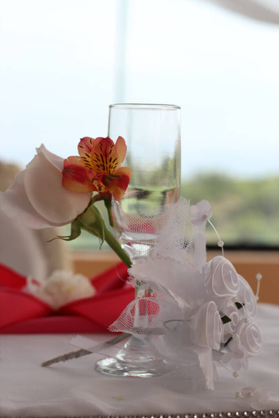 Primer plano de copa de cristal decorada con flores y cintas para que la novia la use en el brindis de los recien casados. Imagen ihanteellinen para promocionar decoraciones y menaje. - Valokuva, kuva
