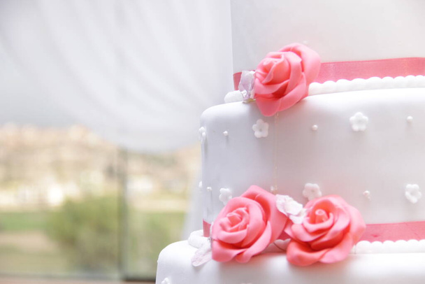 Detalle en primer plano de torta de matrimonio color blanco con decacion de rosas come stistibles en masa elastica. Imagen ideal para promocionar pastelya. - Fotoğraf, Görsel