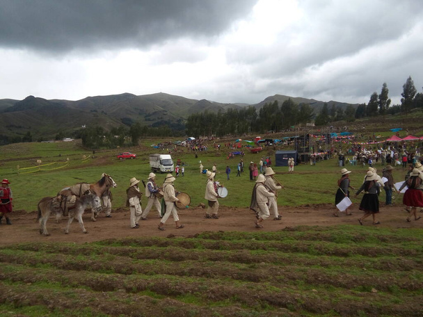 Pasacalles con danzas, musicos y animales oriundos en la sierra del Peru, por fiesta patronal, a lo lejos se observa en contraste de los cerros con el cielo a punto de nublarse - Zdjęcie, obraz