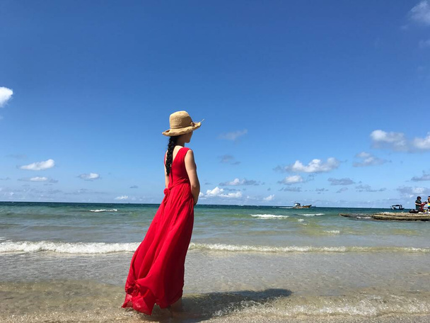 beautiful woman in a red dress on the beach - Фото, изображение