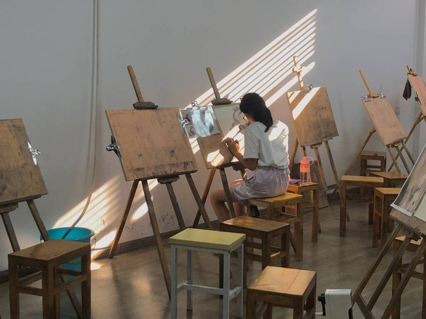 artist painting on easel in studio - Fotó, kép