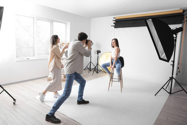 Photographer taking picture of stylish young woman in studio - Photo, Image