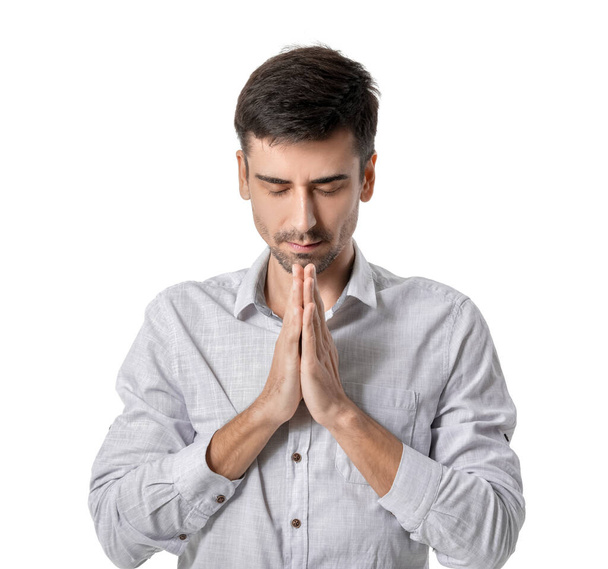 Religious young man praying on white background - Foto, afbeelding