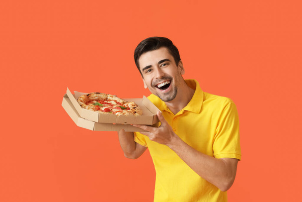 Szczęśliwy młody człowiek ze smaczną pizzą na tle koloru - Zdjęcie, obraz