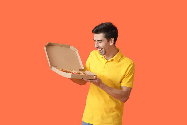 Bello uomo con gustosa pizza su sfondo colore - Foto, immagini