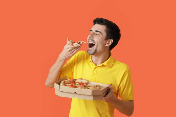 Schöner Mann, der leckere Pizza auf farbigem Hintergrund isst - Foto, Bild