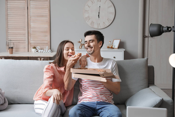 Νεαρό ζευγάρι τρώει νόστιμη πίτσα στο σπίτι - Φωτογραφία, εικόνα