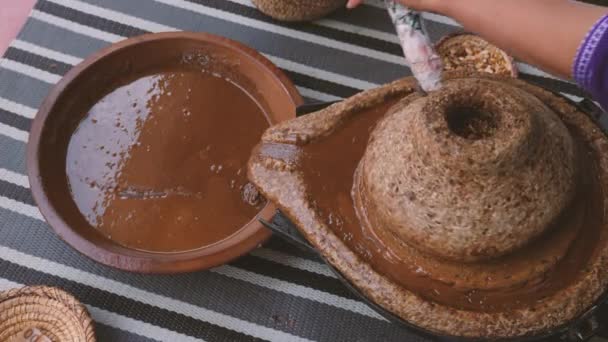 Hagyományos marokkói malomkő, őrlőkő, ahol az argán magokat őrlik. A pasztát a híres argán olaj kivonására fogják használni. Az olaj zsírsavakban gazdag, és a főzéshez és kozmetikumokhoz használják.. - Felvétel, videó