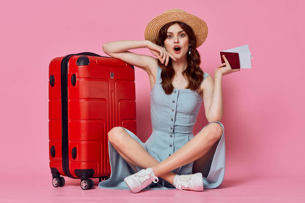 pretty woman in hat sits next to suitcase passport and plane tickets flight - Photo, Image
