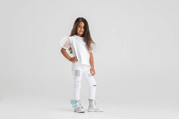Portrait of little Caucasian cute girl posing, standing isolated over white studio background. - Foto, imagen