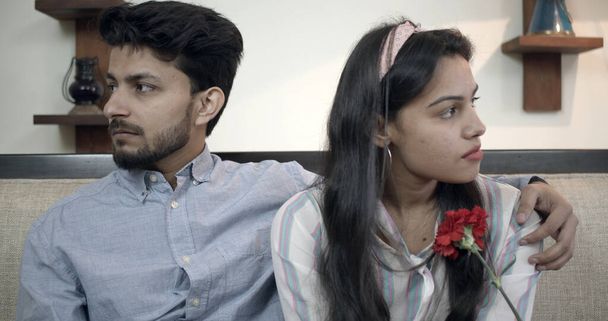A young Indian couple looking in different directions while sitting on a sofa - Fotoğraf, Görsel