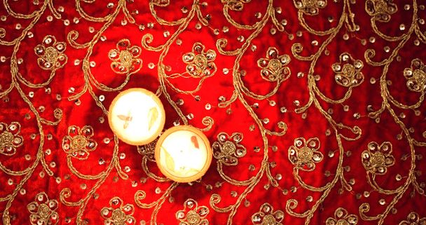 a top view of lit candles on patterned red cloth with shining stones - Фото, изображение
