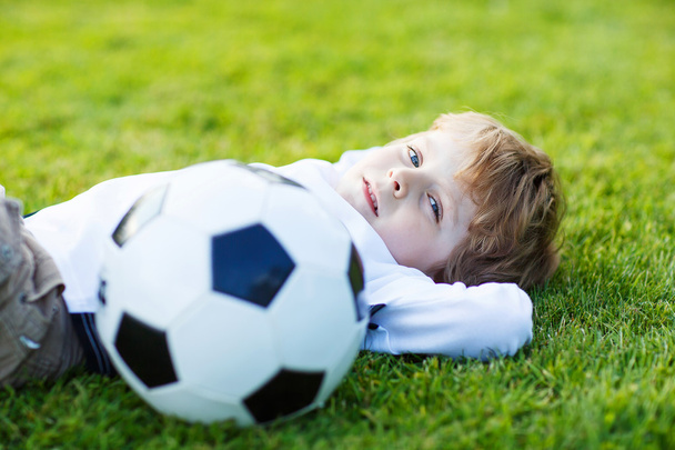 4 フットボール競技場のフットボールで休んでの金髪の少年 - 写真・画像