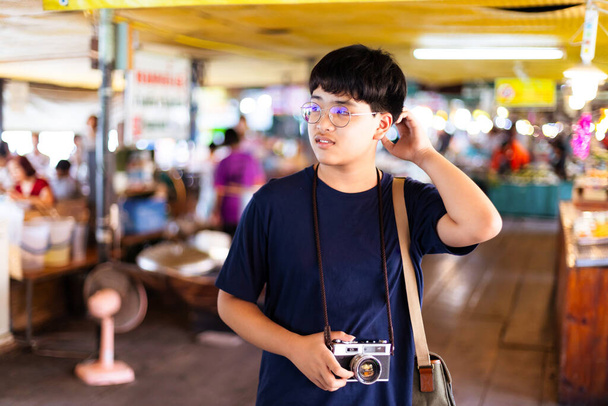 Азиатские мальчики-подростки держат винтажную кинокамеру и фотографируют на туристических достопримечательностях. - Фото, изображение
