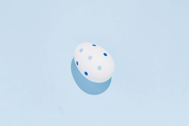 Wit beschilderd ei op de effen blauwe achtergrond concept microbiologie begin van het leven concept - Foto, afbeelding