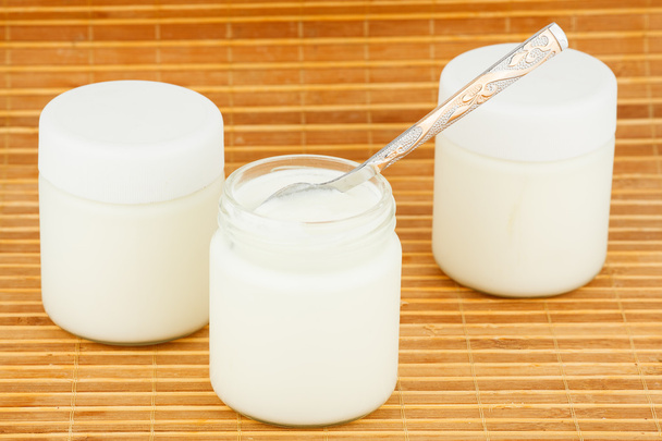 Three jars with home yoghurt on a straw mat - Фото, изображение