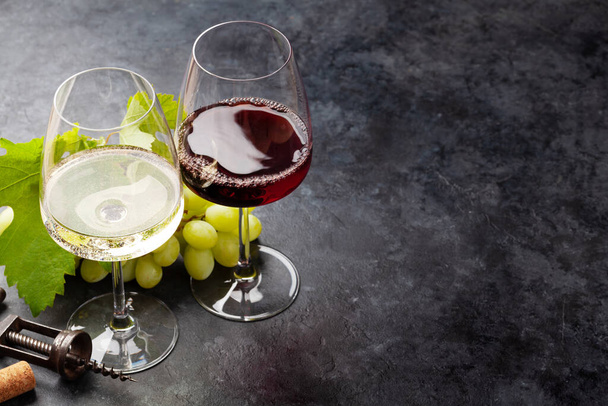 Copas de vino blanco y tinto y uva blanca en mesa de piedra con espacio para copiar - Foto, imagen