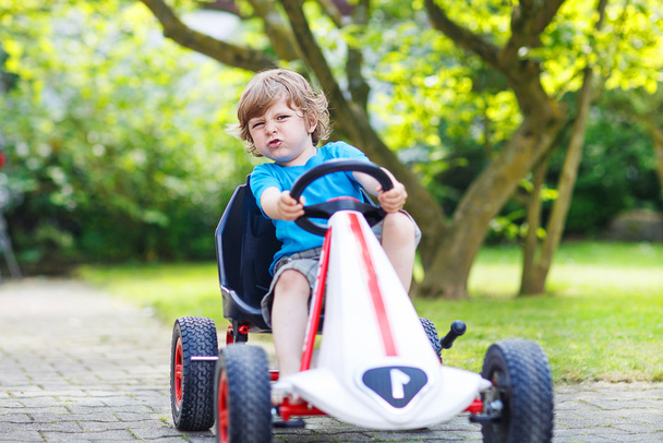 Niño pequeño activo que se divierte y conduce un coche de juguete
 - Foto, imagen
