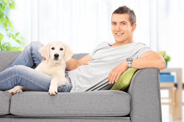 Guy on couch with puppy - Foto, immagini