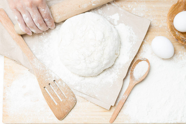 Raw yeast dough on a floured kitchen table, recipe idea. The concept of home baking or making dough. Rolling pin for dough - Foto, Imagen