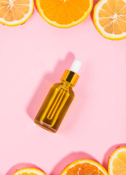 Вітамін С сироваткова пляшка з крапельницею на рожевому фоні з апельсиновими цитрусовими скибочками
 - Фото, зображення