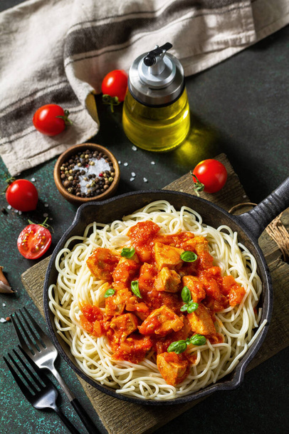 Healthy food, Italian pasta. Spaghetti with chicken and vegetables in tomato sauce in a cast iron skillet on a stone countertop. - Photo, Image