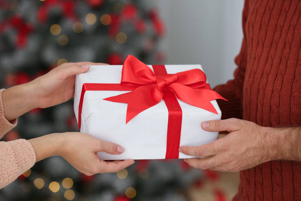 Couple with Christmas gift at home, closeup - Foto, Imagen