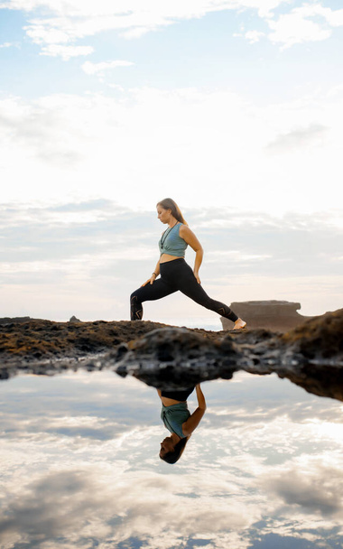 Дівчинка робить йогу біля моря, стоячи у воді. Йога на сонці
 - Фото, зображення