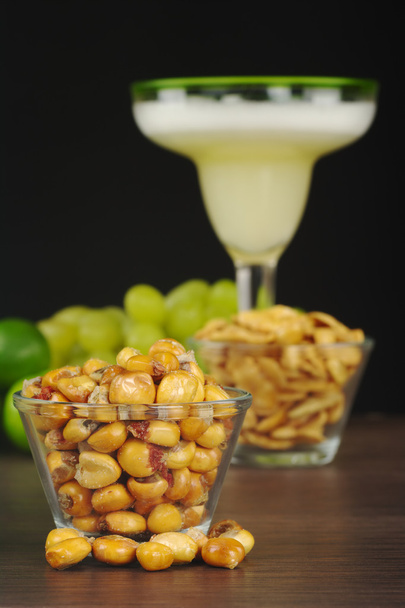 Canchas: Peruvian roasted corn eaten as snack with the cocktail called Pisco Sour in the back with limes and grapes (Selective Focus, Focus on the front) - Photo, Image