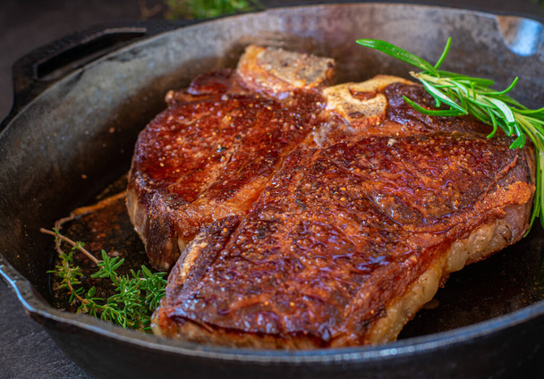 Frisch gebratenes Porterhouse Steak trocken gealtert und Grasfutterfleisch in einer rustikalen gusseisernen Pfanne. Nahaufnahme und isolierte Sicht - Foto, Bild