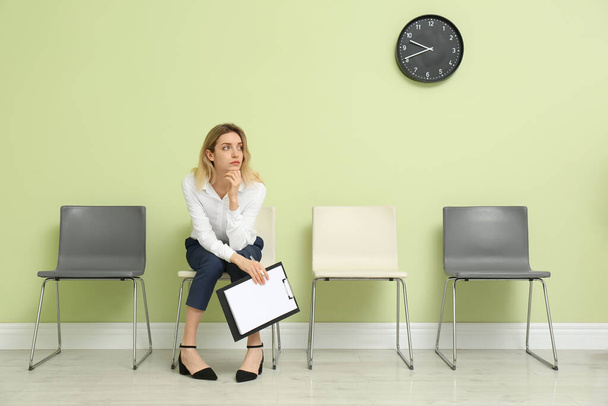 Young woman with clipboard waiting for job interview indoors - Foto, immagini