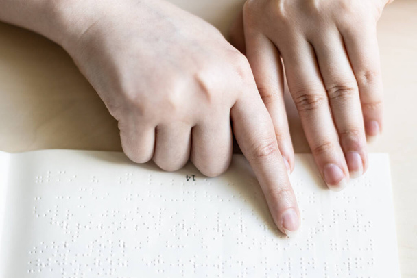 front view of blind woman reads book in braille close up - 写真・画像