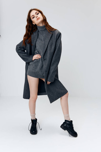 glamorous woman in a sweater and coat on a light background boots naked legs - Foto, afbeelding