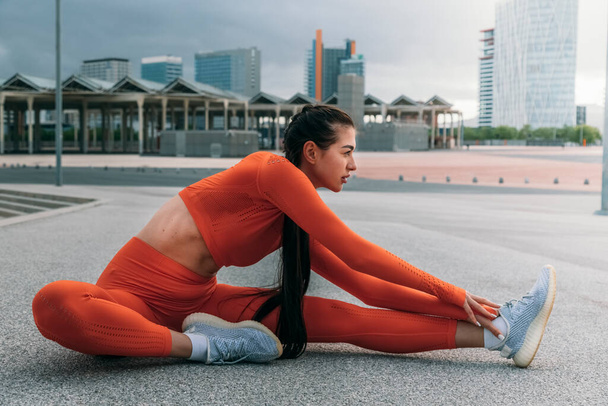 Sportlerin streckt Bein vor dem Laufen. Junge kaukasische Frau morgens Workout-Routine. Sportkonzept. Aktives Konzept für einen gesunden Lebensstil. - Foto, Bild