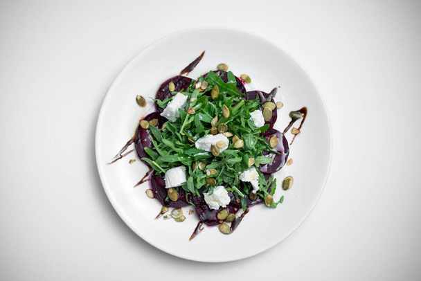 top view of salad with beet, arugula or feta cheese on plate on white background - Φωτογραφία, εικόνα