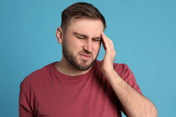 Man suffering from migraine on light blue background - Foto, imagen